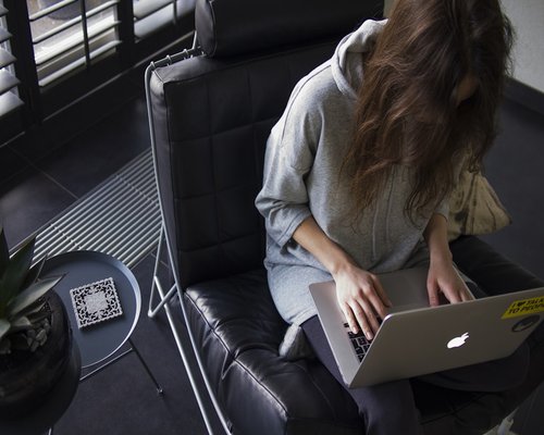 A person typing on a laptop sitting on a comfortable chair